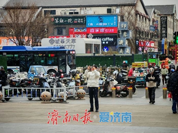 济南迎来今冬初雪 引行人驻足拍照留念