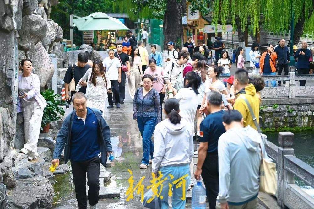凉意来袭，市民游客换上秋装打卡护城河泉景