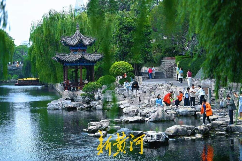 凉意来袭，市民游客换上秋装打卡护城河泉景