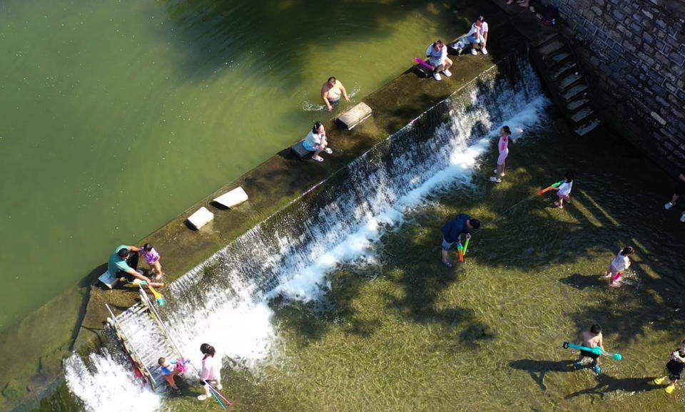 济南连续降雨后玉符河流水潺潺，孩子们尽情玩水