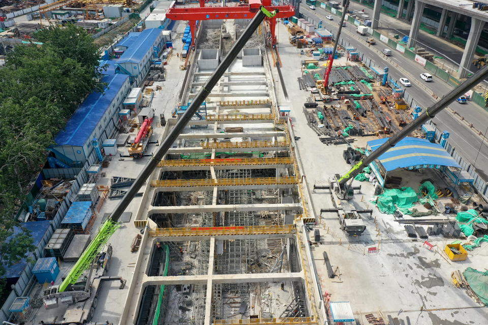 各种大型机械在忙着施工,工人们在车站地下操作面铺设钢筋,浇筑混凝土