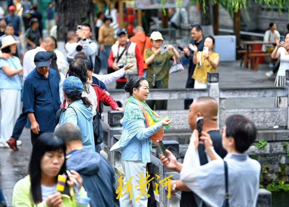 凉意来袭，市民游客换上秋装打卡护城河泉景
