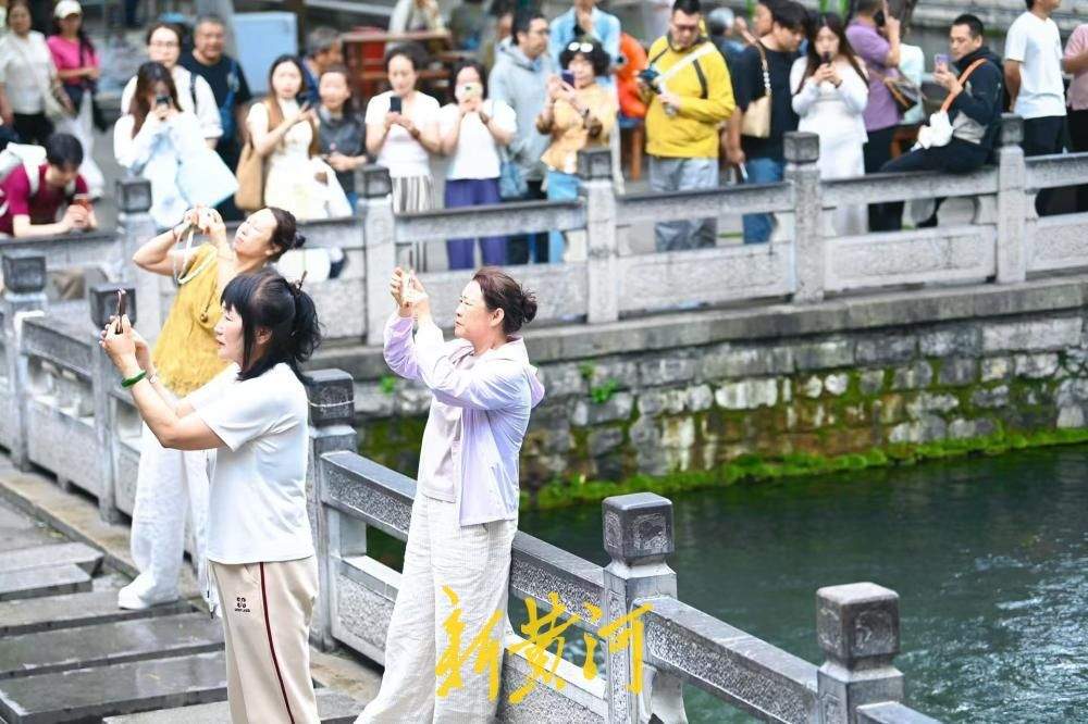 凉意来袭，市民游客换上秋装打卡护城河泉景